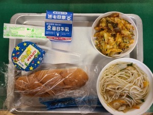 銀色のお盆にパンや牛乳、おかずなどが置かれている写真