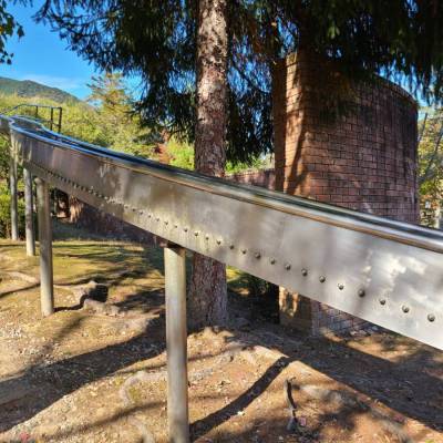 灰色のステンレスのような素材で作られていて、スタート地点が見えないほど長い余暇村公園の滑り台の写真