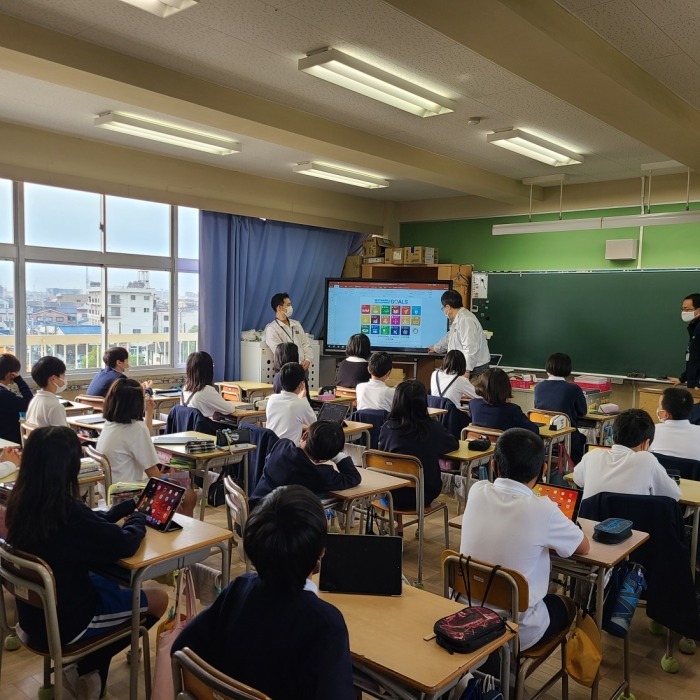 SDGsのロゴアイコンが写っているモニターを生徒たちが見ながら授業を受けている写真