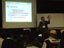 佐太小学校の児童が、プロジェクターを使って出前授業を行うパナソニック株式会社の講師の話を聞いている様子を写した写真