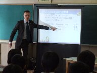 南小学校の児童が、プロジェクターを使って出前授業を行うパナソニック株式会社の講師の話を聞いている様子を写した写真