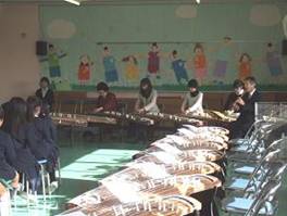 滝井小学校の児童が、大阪音楽大学の中島名誉教授、尺八の塚本氏による「春の海」等の演奏を鑑賞している様子を写した写真