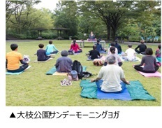 「大枝公園サンデーモーニングヨガ」とキャプションがついた、十数人の人が下にシートを敷きヨガを行っている様子を写した写真