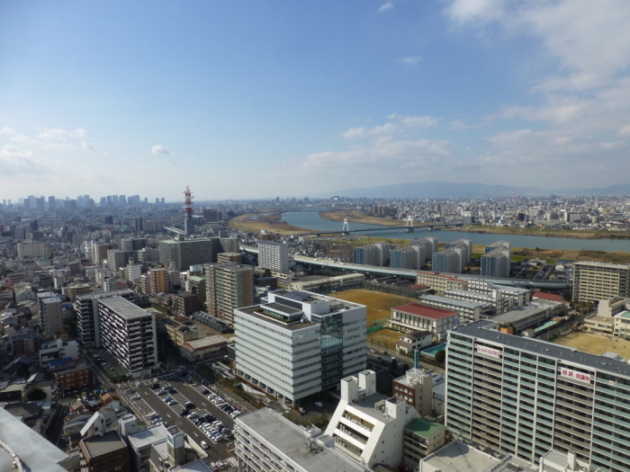 青空の下でビルが立ち並ぶ中、淀川が流れている写真