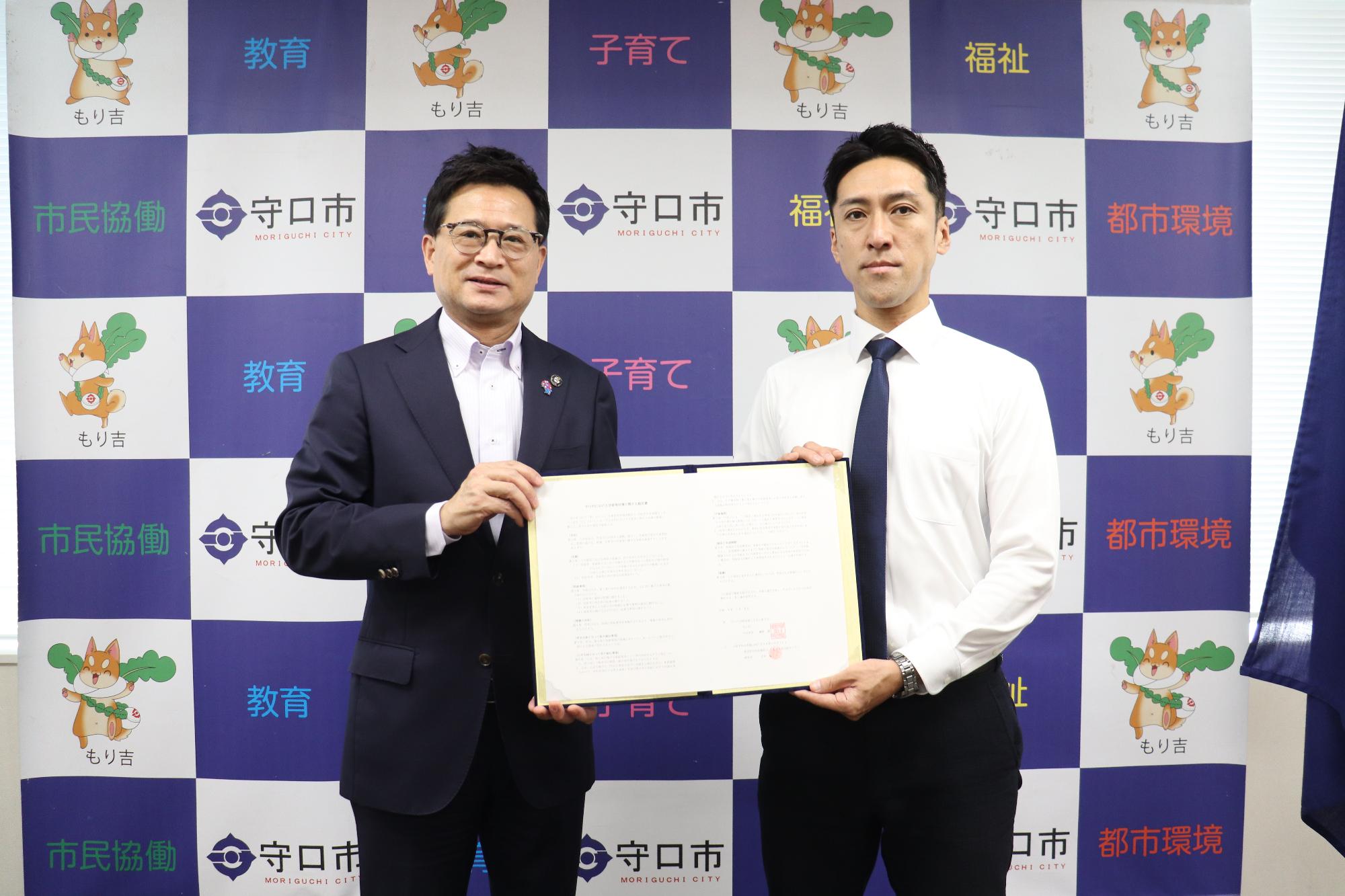 守口市長と特定非営利活動法人 大阪空き家相談センターの関係者の方が協定書を広げて持ち、並んで写っている写真