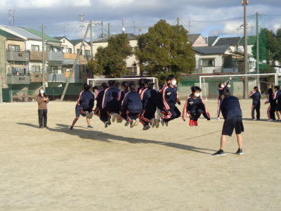 校庭で大縄跳びを跳んでいる生徒たちの写真