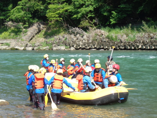 着水している黄色いゴムボートの上や、周りにパドルを持った学生が集まっている写真