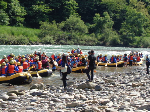 救命胴衣やウェットスーツを着た学生が、黄色いゴムボートの上にのって着水している写真