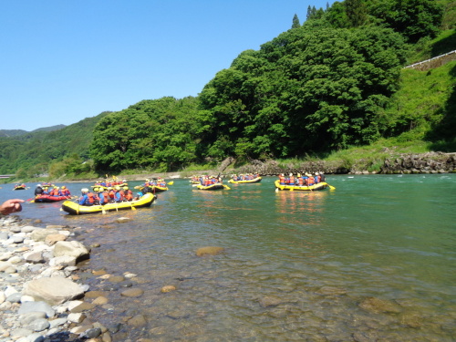 黄色や赤のゴムボートの上の学生が浅瀬や奥の方で着水している写真