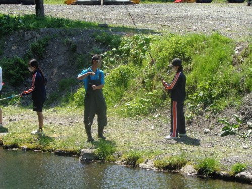 釣り竿を持った学生と、青いシャツの男性が向かいあっている写真