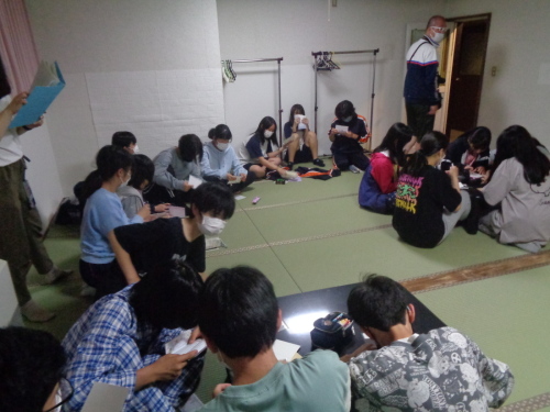畳の部屋に集まって、何か書いている学生たちの写真