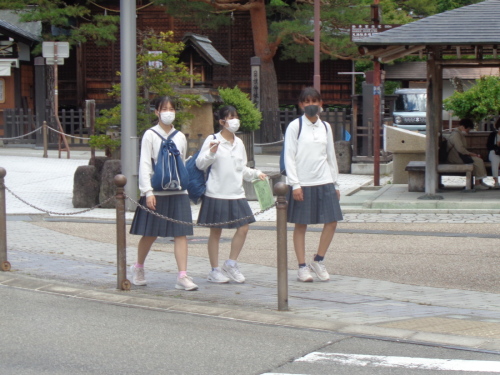 3名の女子学生が歩道を歩いている写真