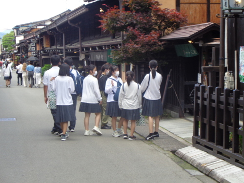 緑ののれんがかかる建物の入り口付近に集まる学生たちの写真