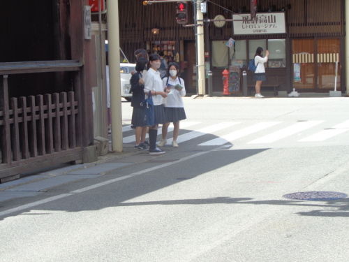 歩道で、手元の資料を見ながら止まっている女子学生3名の写真