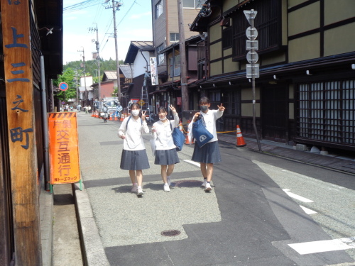 3人の女子学生が、ピースサインをしながら歩いている写真