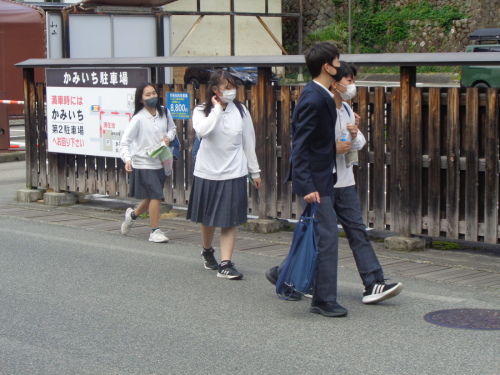 駐車場の横を歩く4名の男女学生の写真