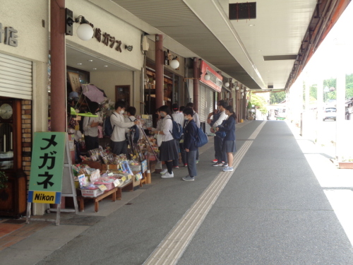 商店街のお店の入り口に並んでいる学生たちの写真