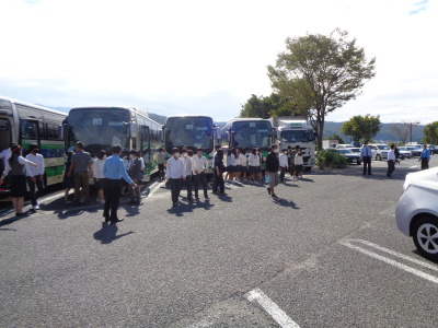 サービスエリアにバスが横並びに停車しており、バスの外に生徒や先生方が出てきている写真