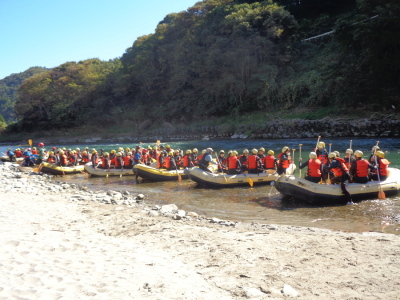 約8名ずつ生徒達が乗ったボートが川岸に並んでいる写真