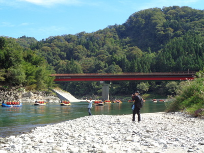 なだらかな川の流れにのって、生徒達の乗ったボートが沢山川をくだっているいる様子の写真