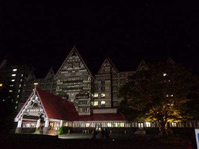 暗闇の中、外灯や建物の灯りで浮かび上がっている赤い屋根の宿舎の外観写真