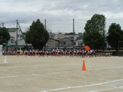 オレンジ色の鉢巻きをした生徒たちが縦一列になって走っている写真