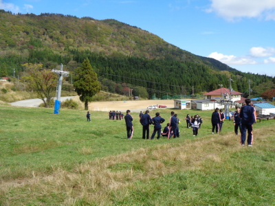 坂道になっている芝生の上に、生徒たちがそれぞれグループに分かれて集まっている写真