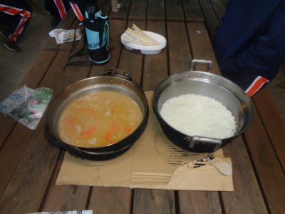 右側には大きな鍋に入ったご飯、左側には大きな鍋に入った豚汁が置かれている写真