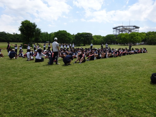 芝生で整列して座っている生徒たちの写真