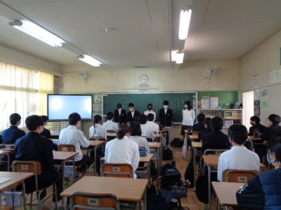 5人の生徒が黒板の前に立ち、他の生徒たちが前方の5人に注目している写真
