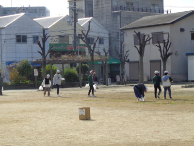 芝生の上で白い帽子を被った子供たちがゴミ拾いをしている写真