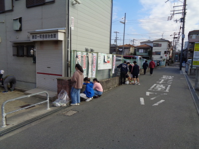 建物の横の側溝を掃除する参加者たちを写している写真