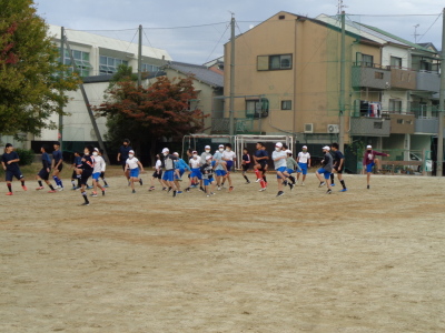 サッカー部員と一緒に足を高く上げて小学生が練習を行っている写真