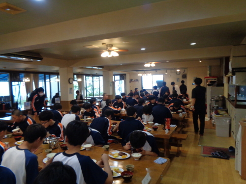 食堂で男子生徒たちが夕食を食べている様子の写真