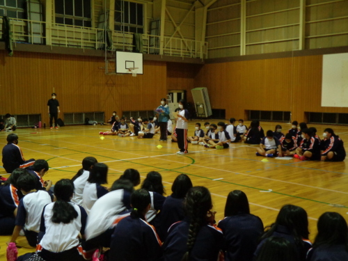 2つの島に分かれた生徒たちの間に女子生徒が立って話をしている写真