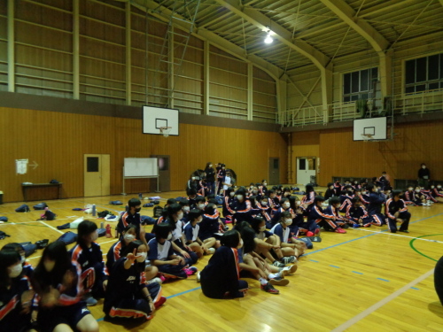 体育館の床に座って右側を見ている女子生徒の写真