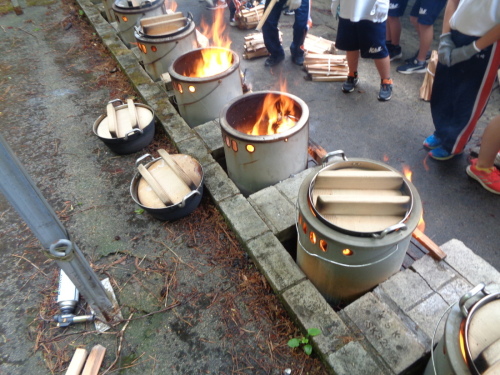調理済みの鍋を横に置いた後釜戸から勢いよく炎が上がっている写真