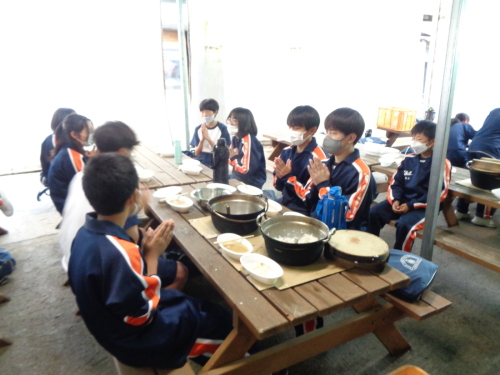 2つの楕円形の容器に分けて入れたご飯とシチューを食べ始める生徒たちの写真