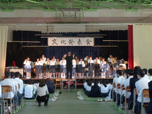 ステージ上で吹奏楽部の部員が立って演奏を行っている様子の写真