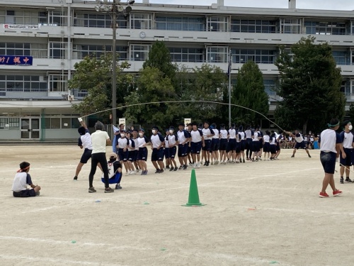 青組の生徒二人が回している長縄の縄が生徒たちの頭上を通っている写真