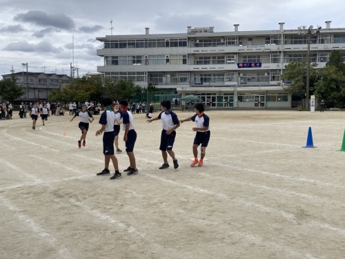 バトンを受け取ろうと白線の上で男子生徒4人が並んでいる様子を後ろから写した写真