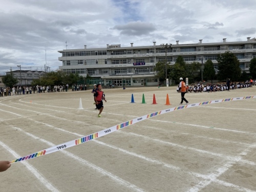 赤組のアンカーの走者がゴールテープに向かって走っている写真