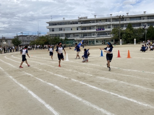 青組の生徒がバトンを受け取ろうと後ろを振り返って手を伸ばしている写真