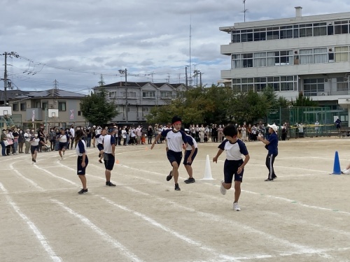 赤組の生徒が次の走者の生徒へバトンを渡そうとしている写真