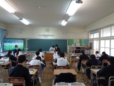 黒板の前に立っている2名の生徒が資料を見ながら学級討議を行っている様子の写真