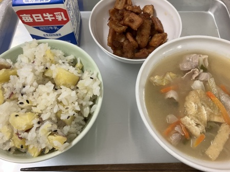 左上に牛乳、時計回りに鶏肉と高野豆腐のからあげ、みそ汁、いもごはんがトレーに並べられた給食の写真