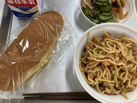 トレイに並べられたミニパンプキンパン・牛乳・ジャージャー麺の給食の写真