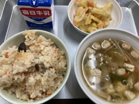 トレイに並べられたしめじごはん・牛乳・すまし汁・さつまいものかきあげの給食の写真