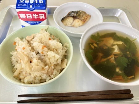 左上に牛乳、時計回りにさばの塩焼き、わかたけ吸物、たけのこごはんがトレーに並べられた給食の写真