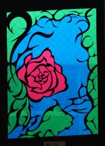 真っ赤な薔薇の周りに黒い線で、とげや茎を表現しているステンドグラスの作品の写真